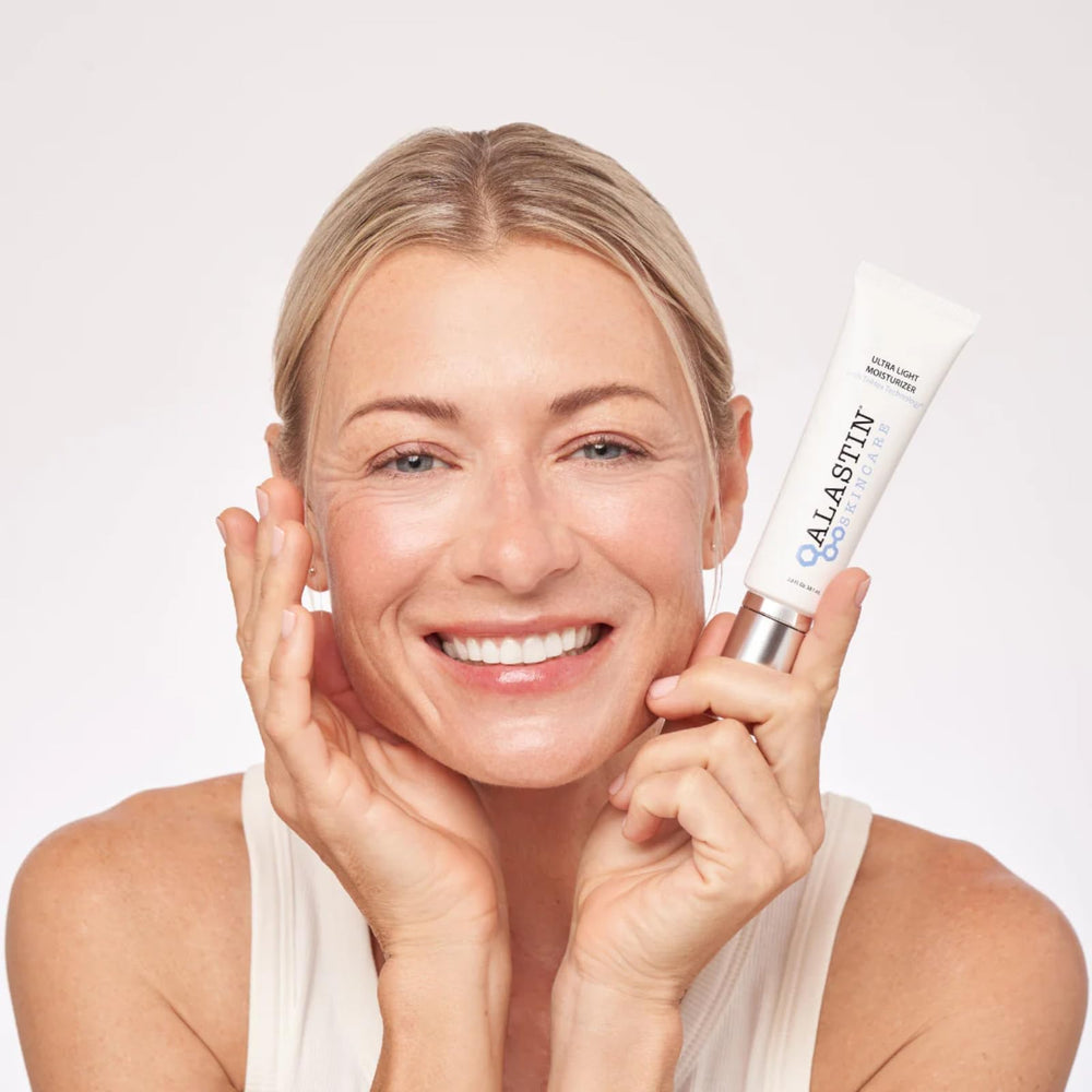 Applying Alastin Ultra Light Daily Moisturizer on face and neck supports daily hydration.