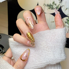 Close-up of CTTHNBD almond nails with gold bow design for events
