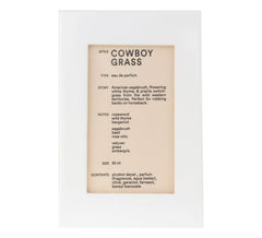 Cowboy Grass bottle on wood surface showing rustic heritage and lasting fragrance