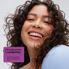 Hands applying Eva NYC Anti-Frizz Conditioner for even distribution.
