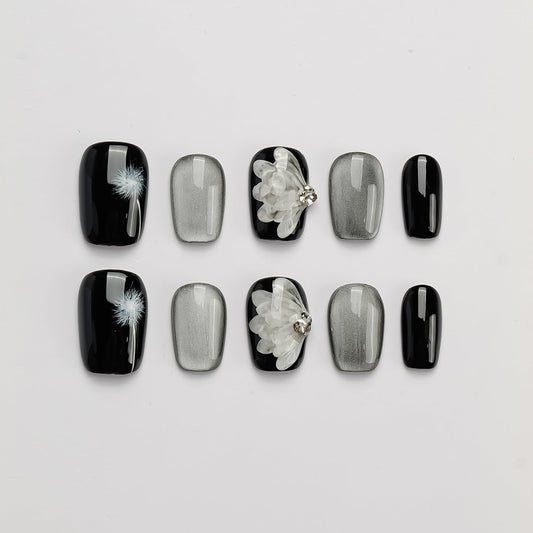 GLORS press-on nails in black and silver with dandelion wing design for chic at-home manicure.
