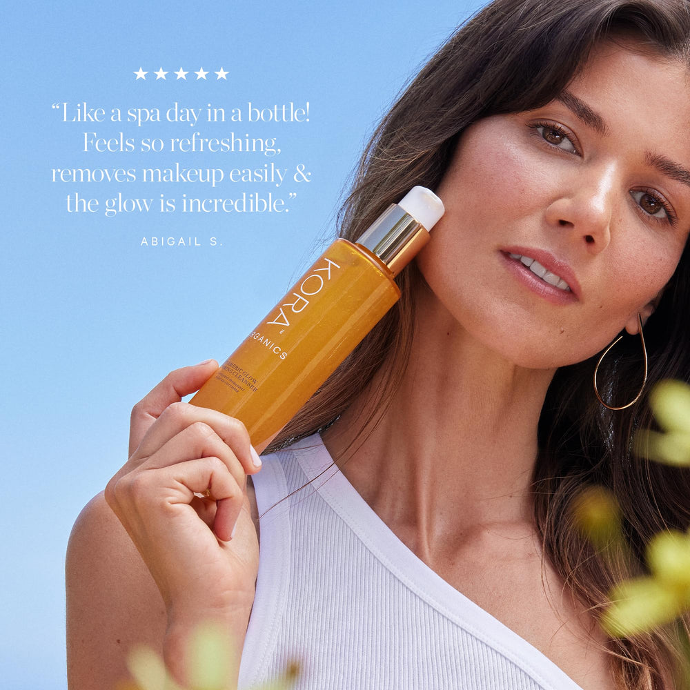 Hands massaging KORA Organics Turmeric Glow Foaming Cleanser on the face (3-5 pumps).