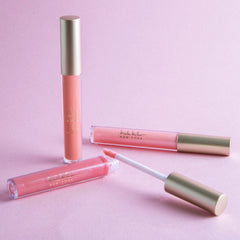 Nicole Miller lip gloss wand applying a shimmering peach shade for radiant lips