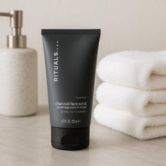 RITUALS Homme Charcoal Face Scrub near a towel, suggesting routine after-shave prep and skin refreshment.