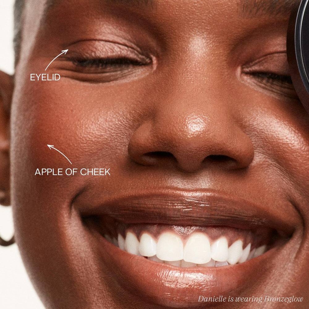 Saie Glow Sculpt large brush applying on the cheekbones for lift and glow.