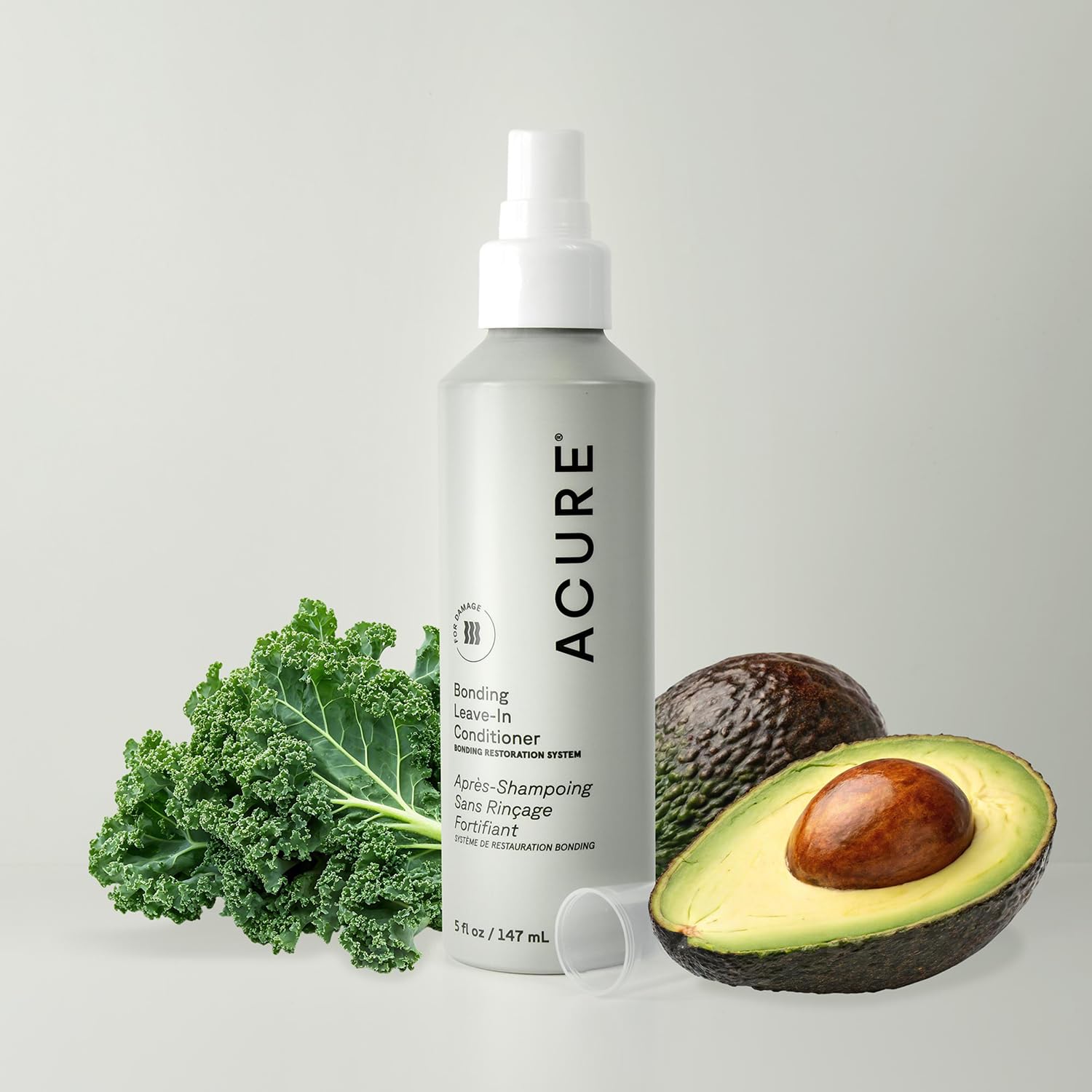 Spraying Acure Bonding Leave-In Conditioner onto mid-length hair for smoothness