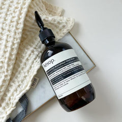 Aesop Resurrection Hand Wash natural ingredients display showing mandarin and rosemary.