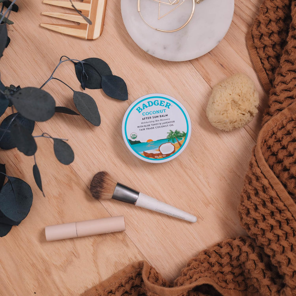 Compact Badger Coconut AfterSun Balm travel tin in a beach bag setup.