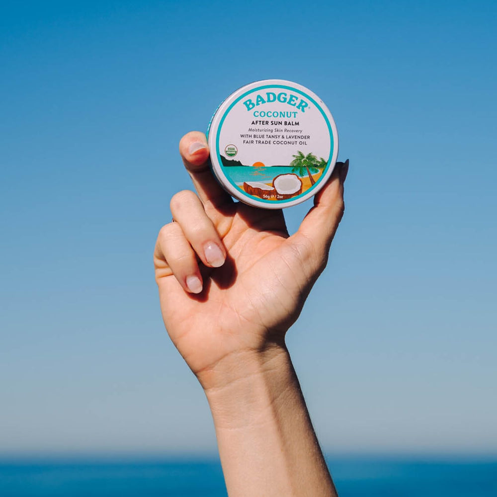 Applying Badger Coconut AfterSun Balm after sun exposure for hydration and soft skin.