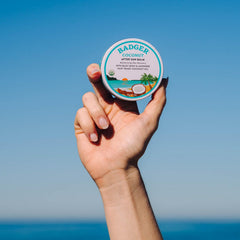 Applying Badger Coconut AfterSun Balm after sun exposure for hydration and soft skin.