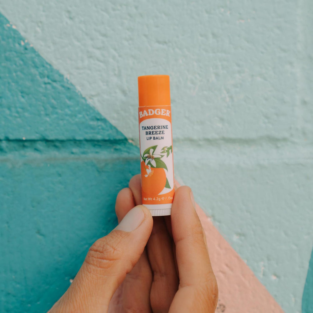 Person applying Badger Tangerine Breeze lip balm for quick moisture refresh