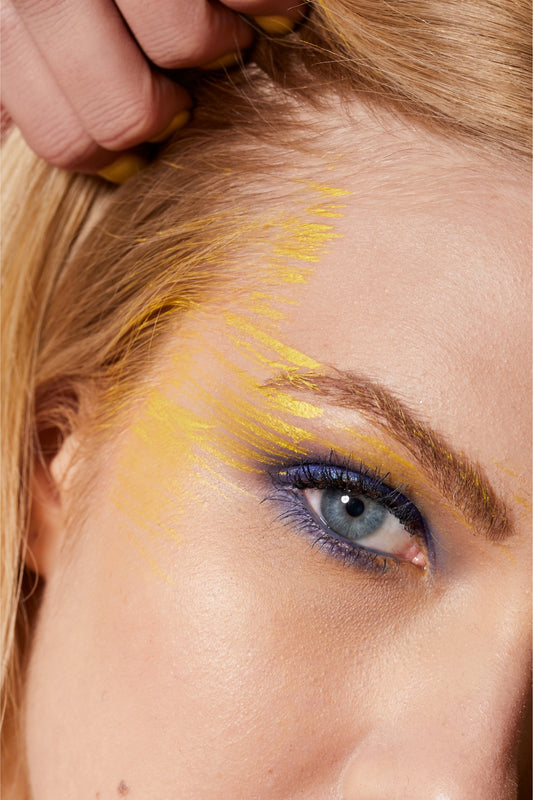 Person applying yellow makeup to their hair with a brush