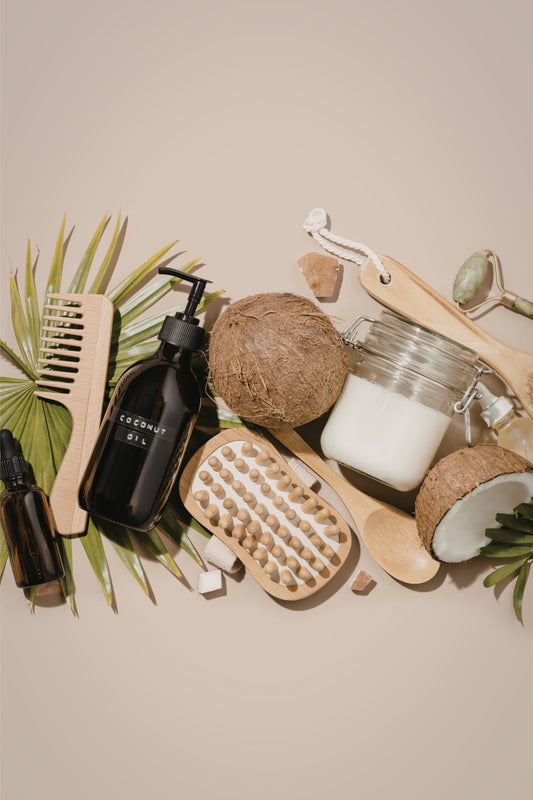 Collection of natural beauty products including a brush, coconut, and jars on a beige background