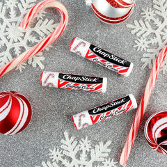 Individual ChapStick Candy Cane stick beside open packaging.