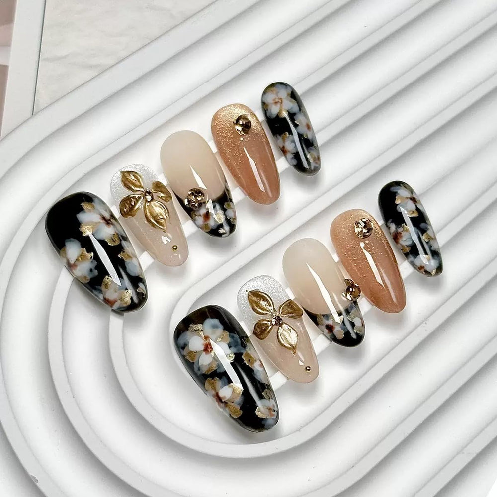 CTTHNBD medium almond nails with black-gold flower design for a glossy finish.