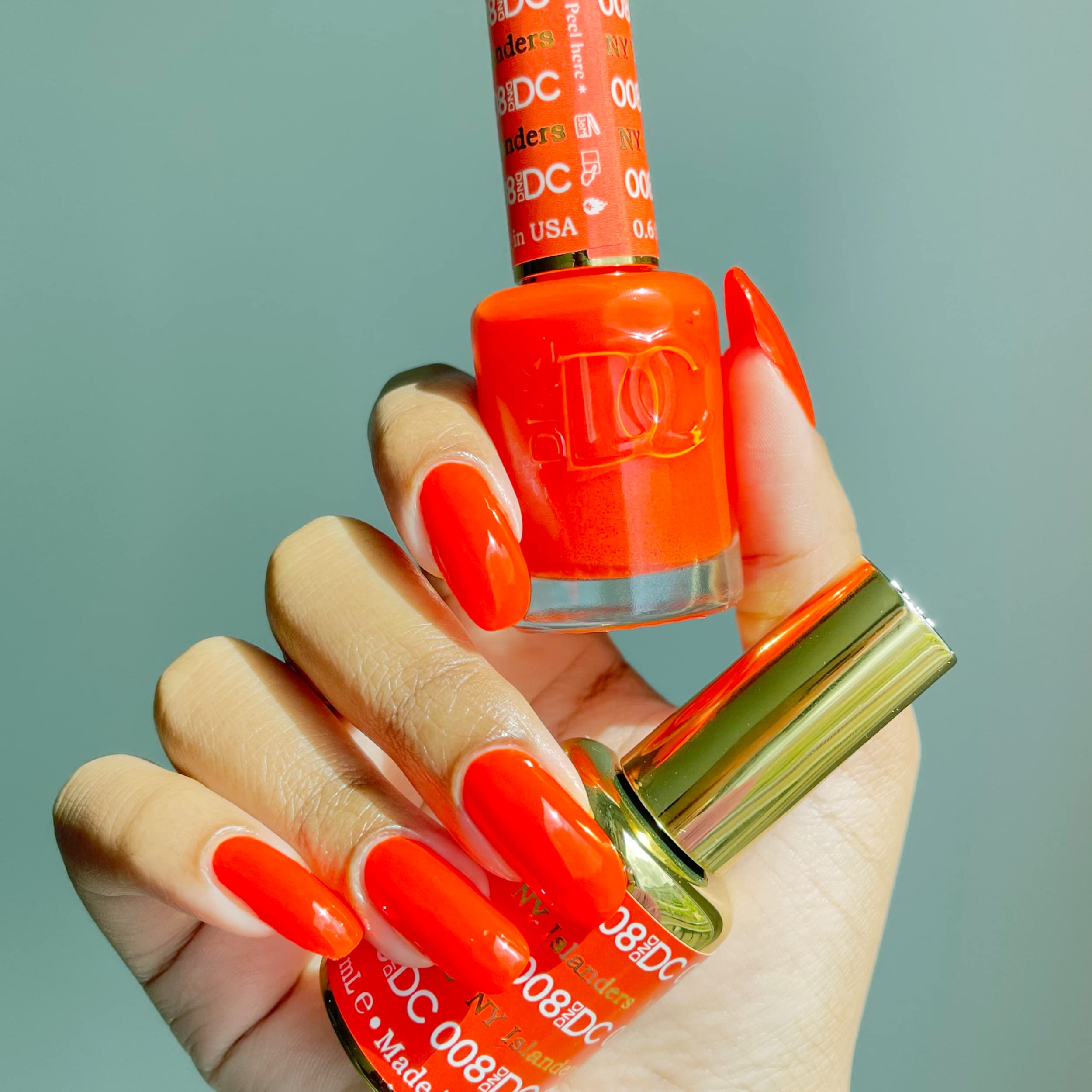 DAISY DND orange lacquer bottle close-up showing chip-free wear potential.
