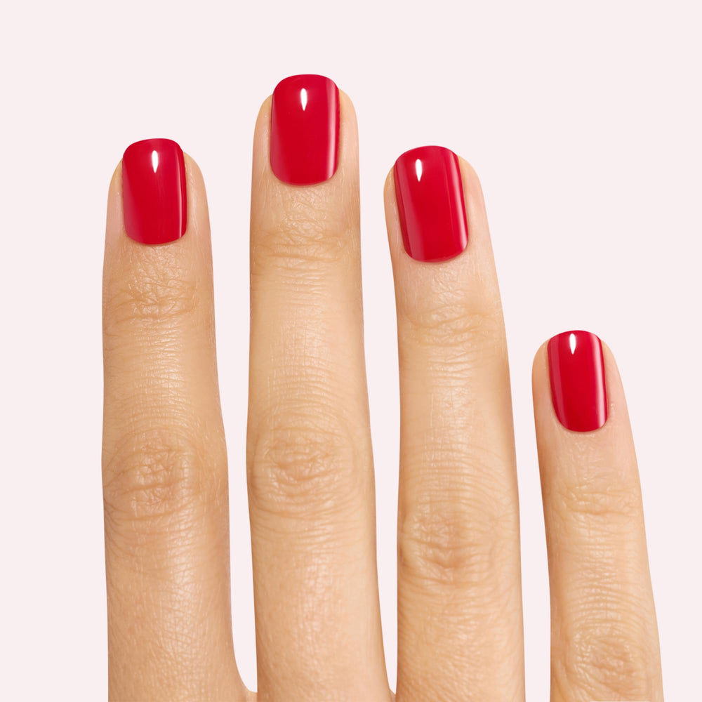 Close-up of Dashing Diva Red Dahlia gloss nail strip on nail.
