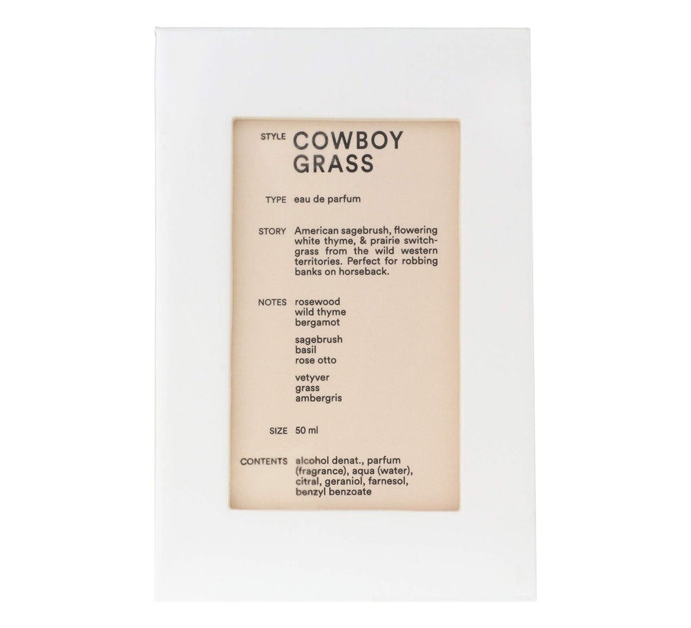 Cowboy Grass bottle on wood surface showing rustic heritage and lasting fragrance