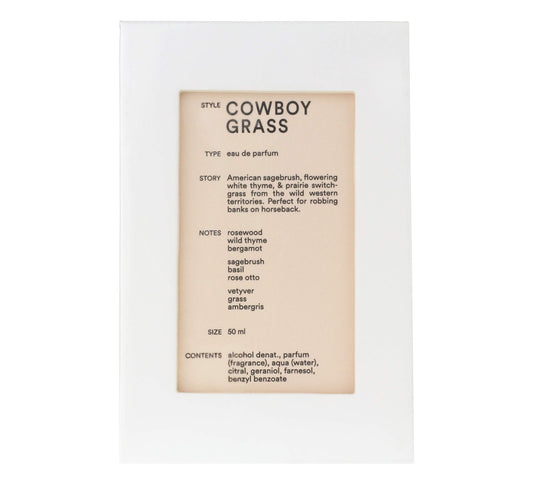 Cowboy Grass bottle on wood surface showing rustic heritage and lasting fragrance
