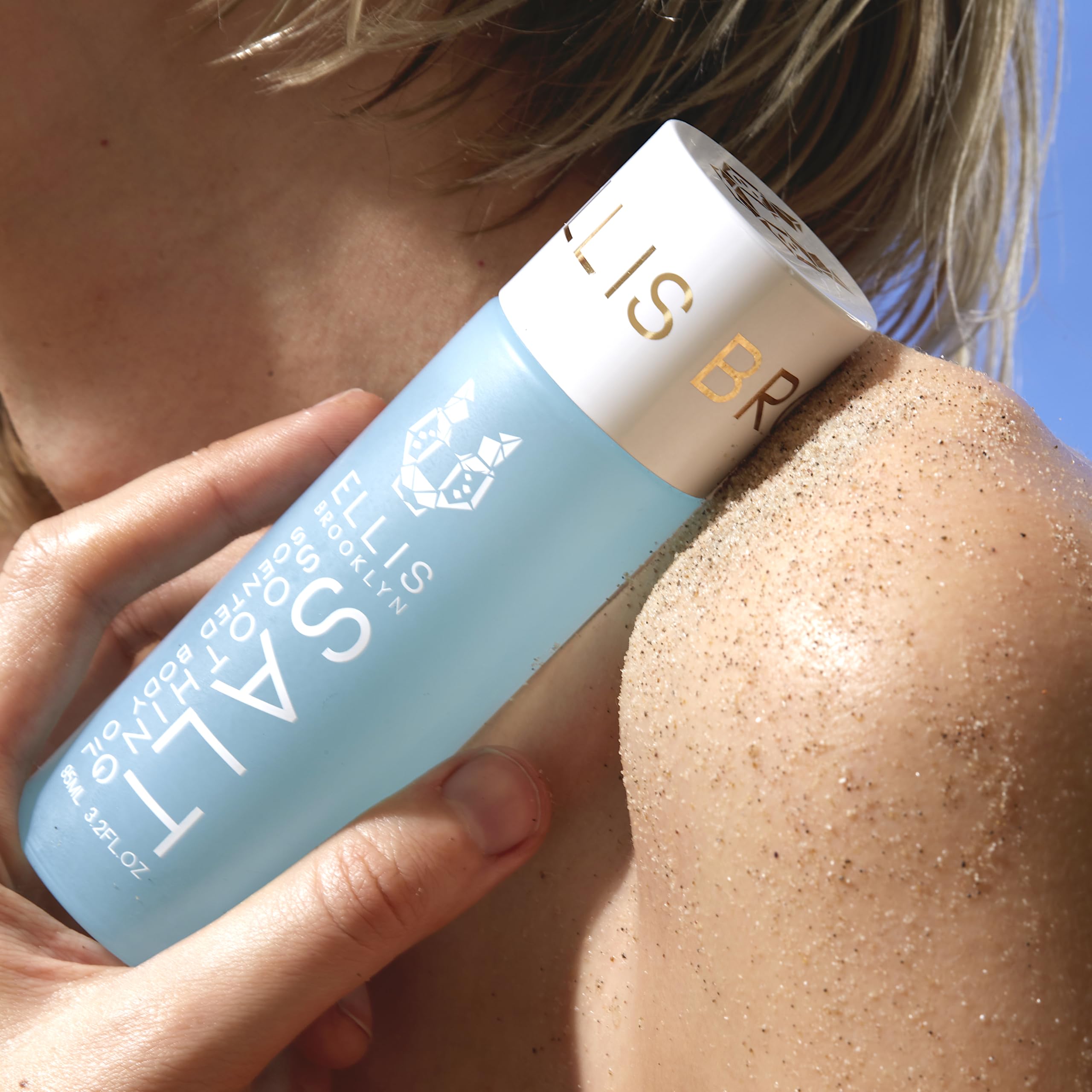 Lifestyle beach scene with Ellis Brooklyn SALT Body Oil conveying coastal luxury and daily self-care.