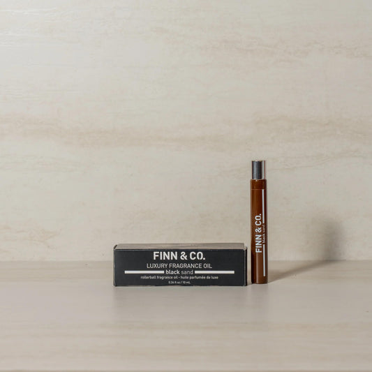 FINN & CO Black Sand bottle at dusk beach scene, warm sandalwood notes.