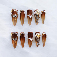 GLORS brown-to-gold ombre stiletto nails with 3D rhinestones for a dramatic look