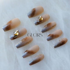GLORS nude-to-gray ombre nails with gold crystals catch light beautifully