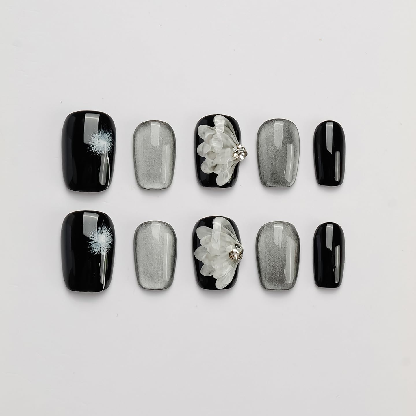 GLORS press-on nails with black base and silver dandelion wing design for chic at-home manicure.