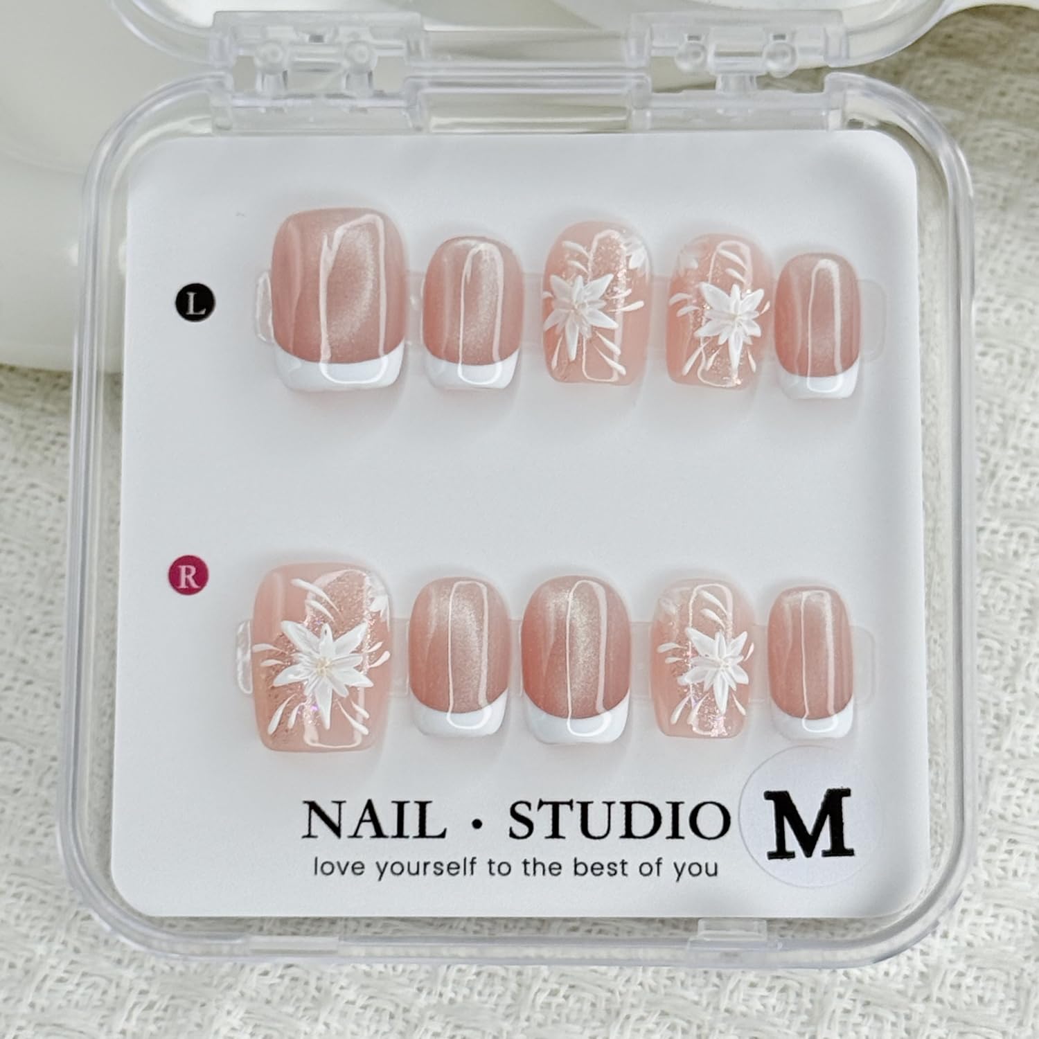 Handmade press-on nails: white French tips with flower designs for a polished look.