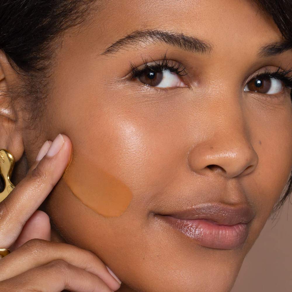 Close-up of ILIA True Skin Serum Foundation bottle on vanity with soft glow.