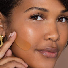 Close-up of ILIA True Skin Serum Foundation bottle on vanity with soft glow.