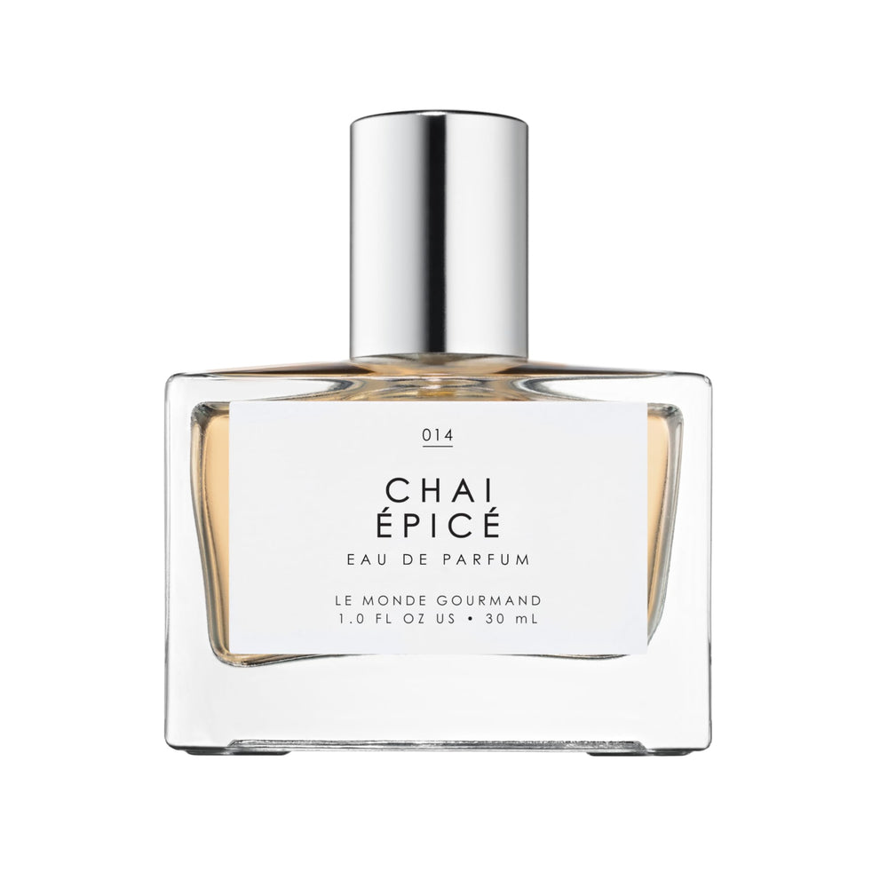 Le Monde Gourmand Chai Épicé spray bottle on wooden surface highlights warm, woody notes.