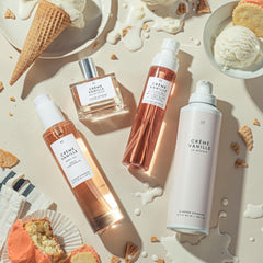 Le Monde Gourmand Crème Vanille bottle on vanity with jasmine backdrop for day-to-night versatility.