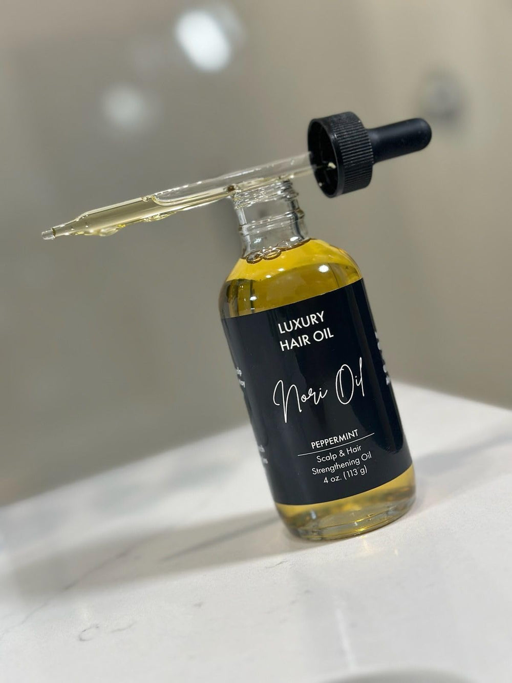 Nori Oil bottle pour with eight-oil blend for hair nourishment and fragrance