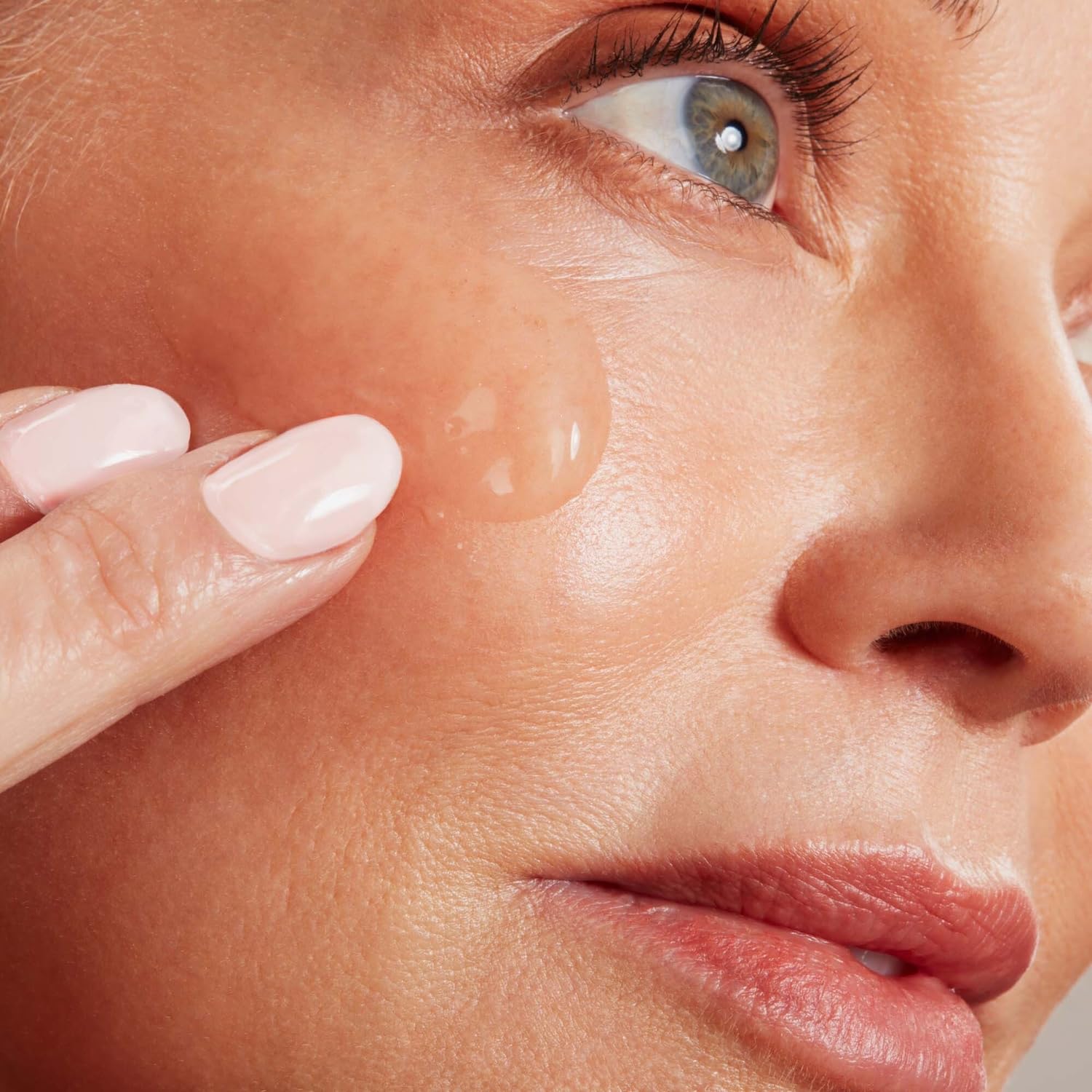 NuFACE applying conductive gel to cheeks for enhanced device performance.