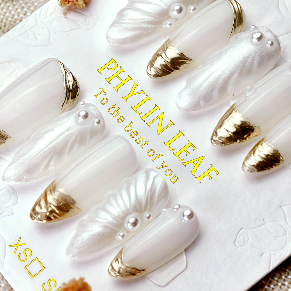 Close-up of PHYLIN LEAF nails highlighting white and gold 3D shell details.