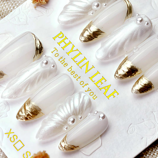 Close-up of PHYLIN LEAF nails highlighting white and gold 3D shell details.