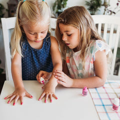 Kids' hands applying Piggy Paint Rainbow Party polish during playtime.