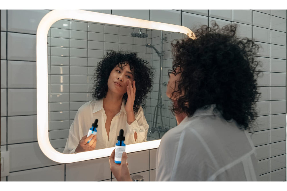 Small bottle shown beside skincare products on a vanity.
