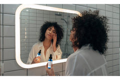 Small bottle shown beside skincare products on a vanity.
