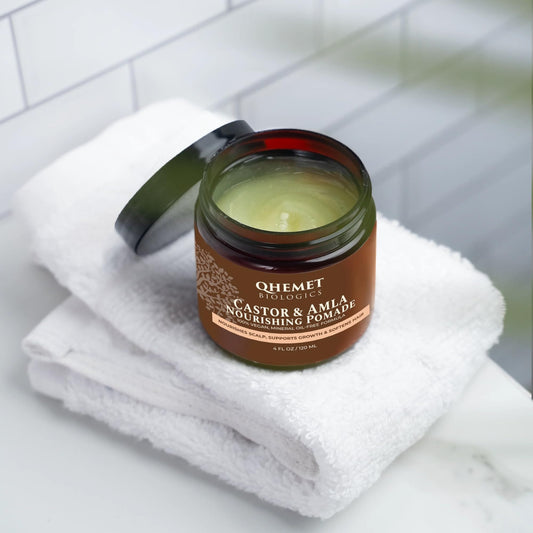 Qhemet Biologics Castor and Amla pomade texture being smoothed into hair for pliability.