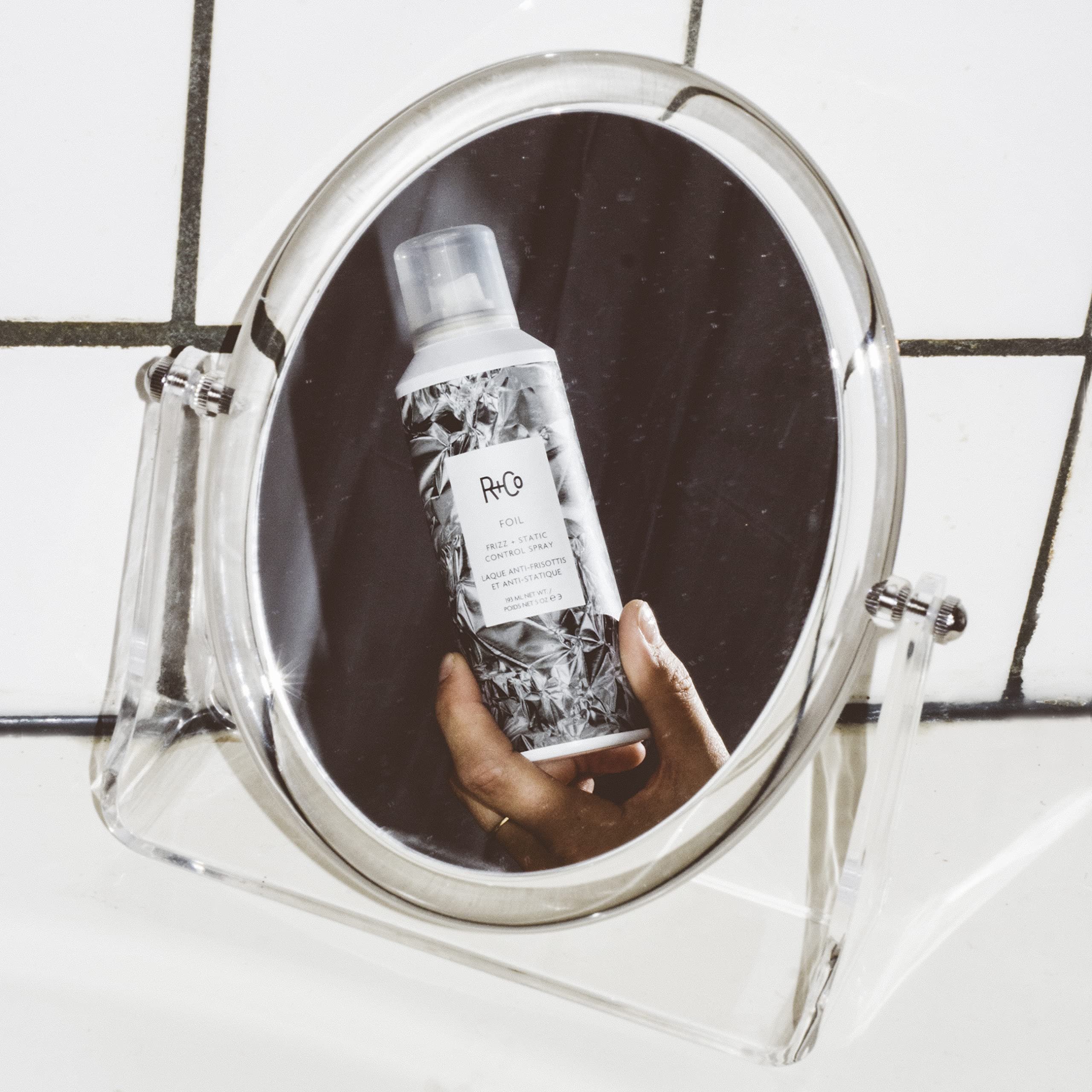 R+Co Foil Frizz + Static Control Spray mist applied to hair for flexible control and shine.