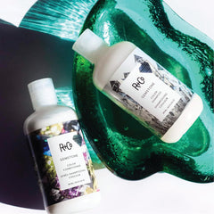 Close-up of R+Co Gemstone Color Conditioner smoothing the hair.