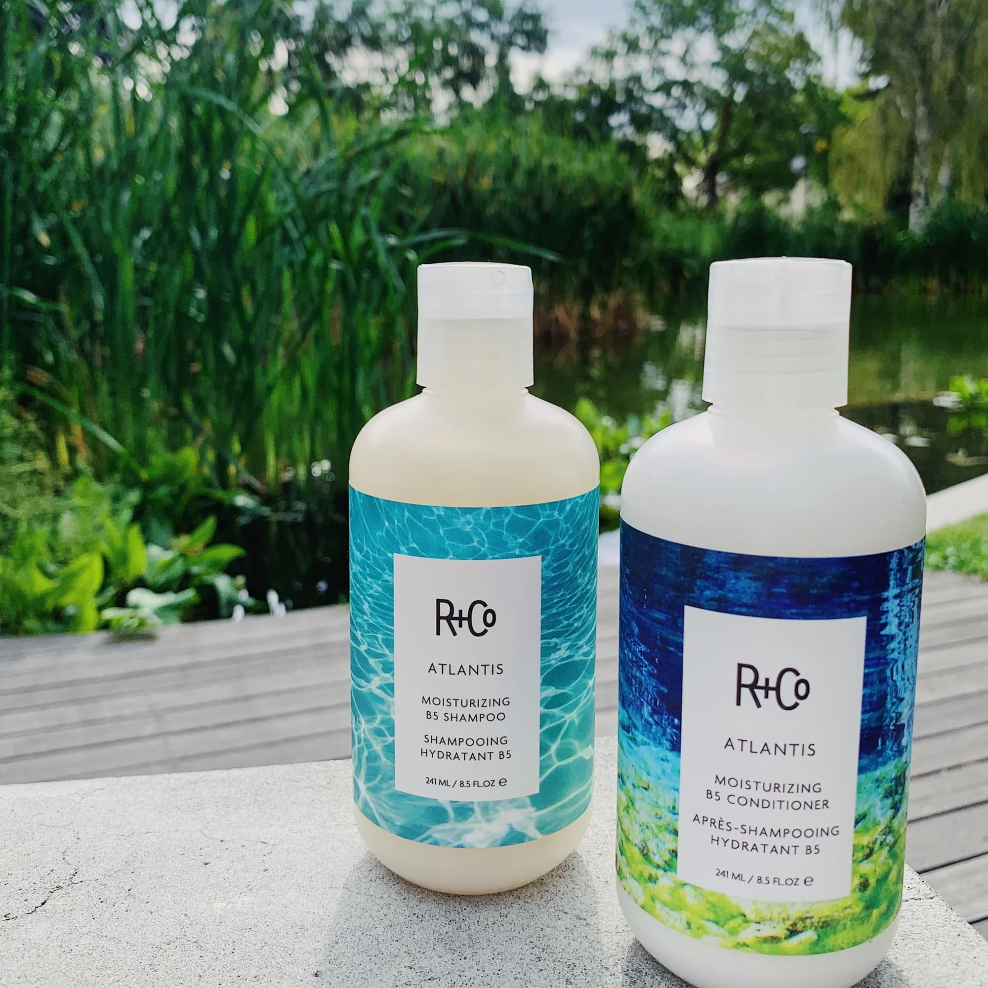 R+Co Atlantis bottle on wet hair emphasizing moisture during washing.