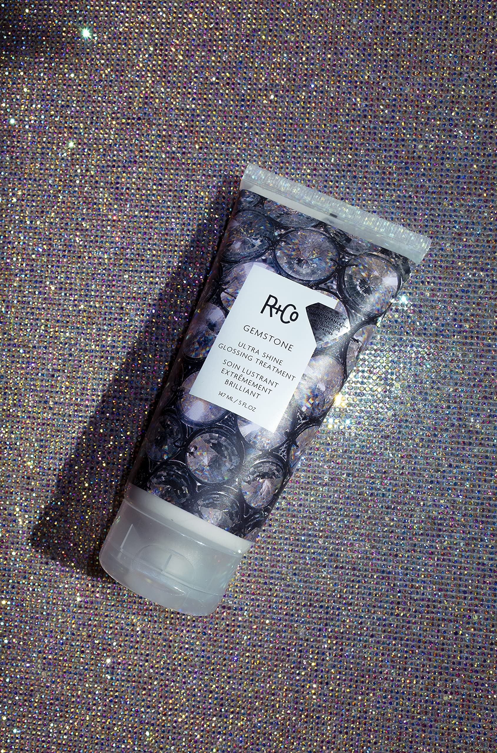 Application shot of R+Co Gemstone Ultra Shine glossing on damp hair.
