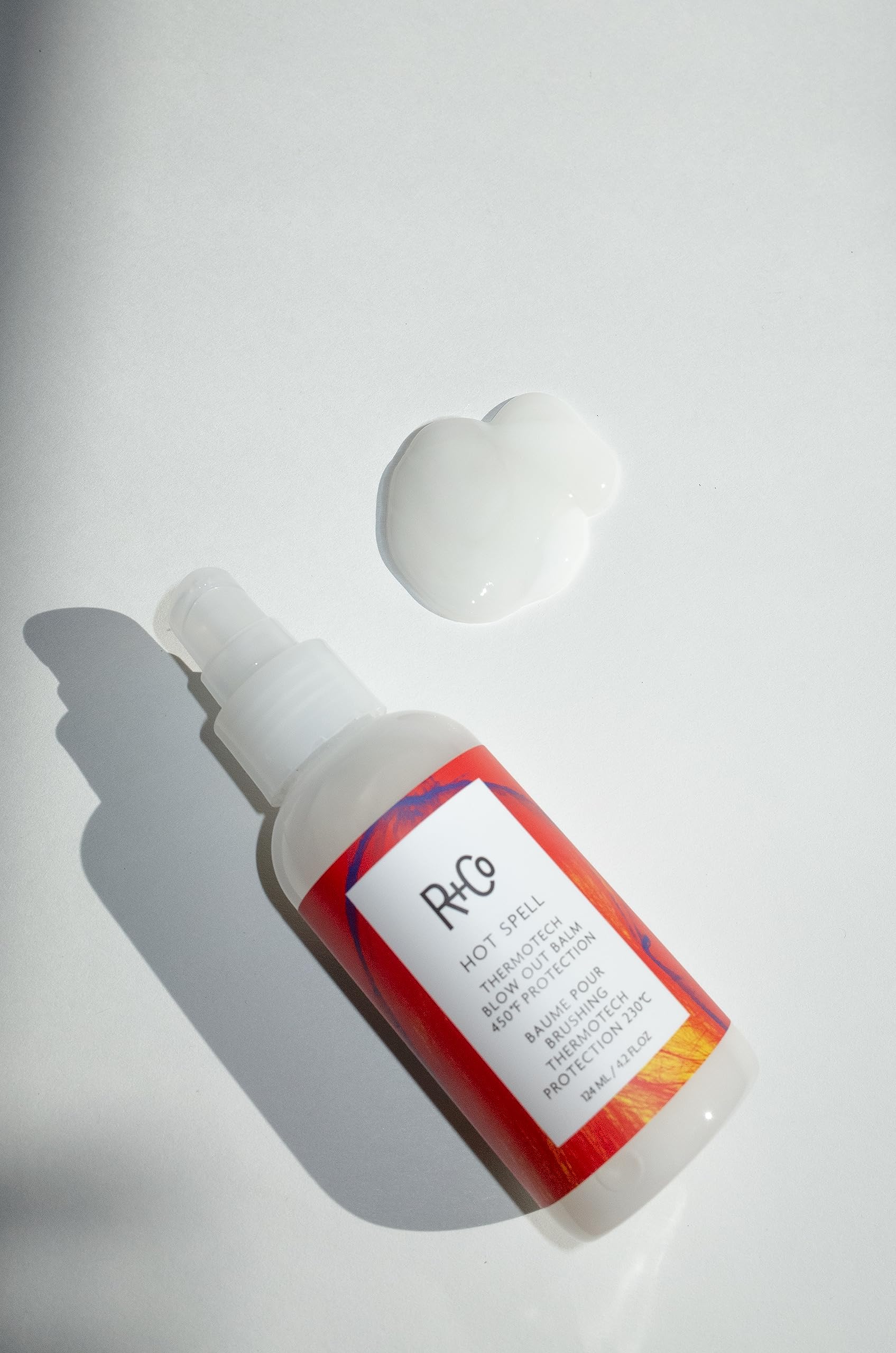 Application close-up of R+Co balm on damp hair for smoothing
