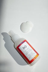Application close-up of R+Co balm on damp hair for smoothing
