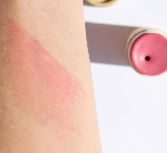 River Organics blush stick swirl on cheek for natural glow.