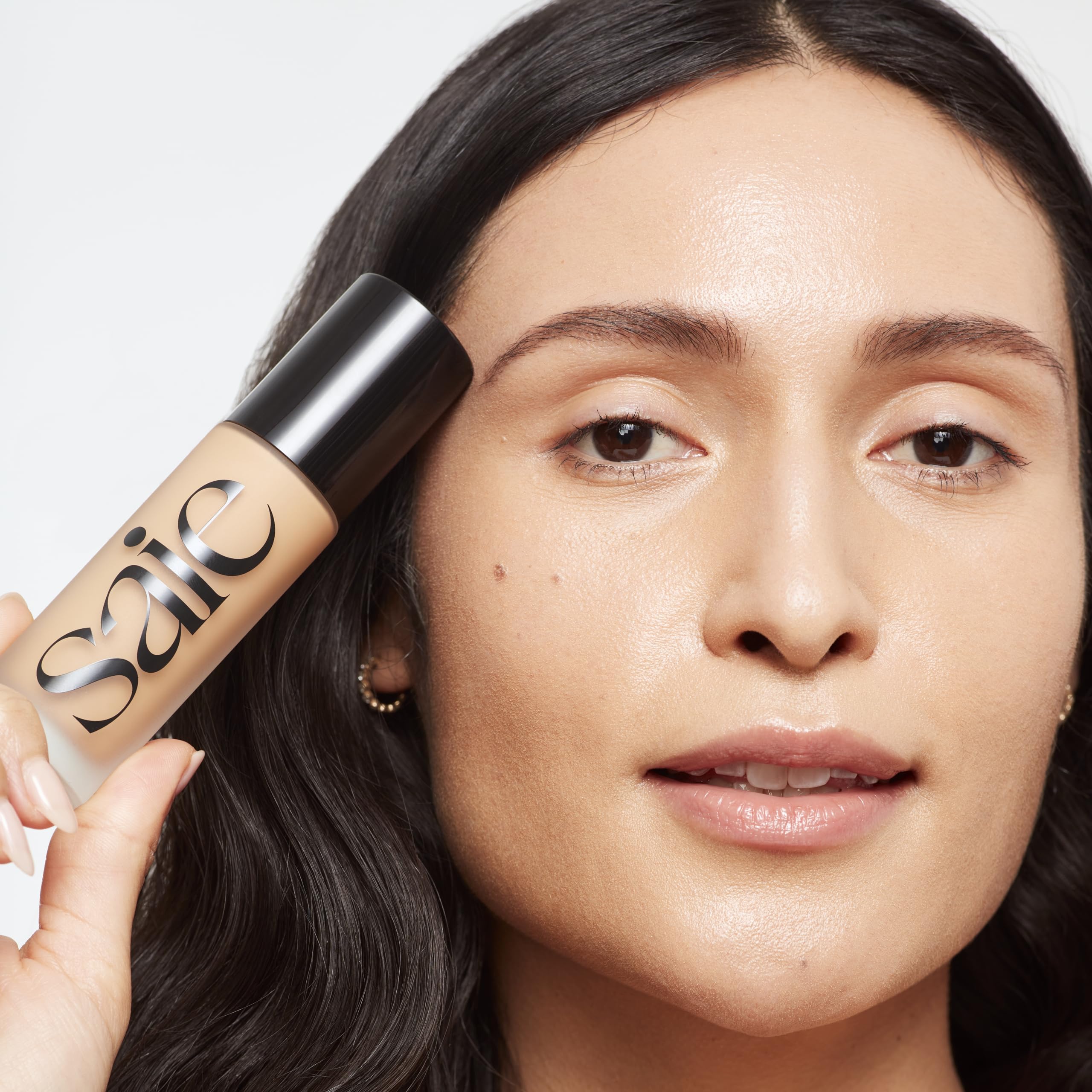 Saie Glowy Super Skin Tint pump onto fingertips for precise application