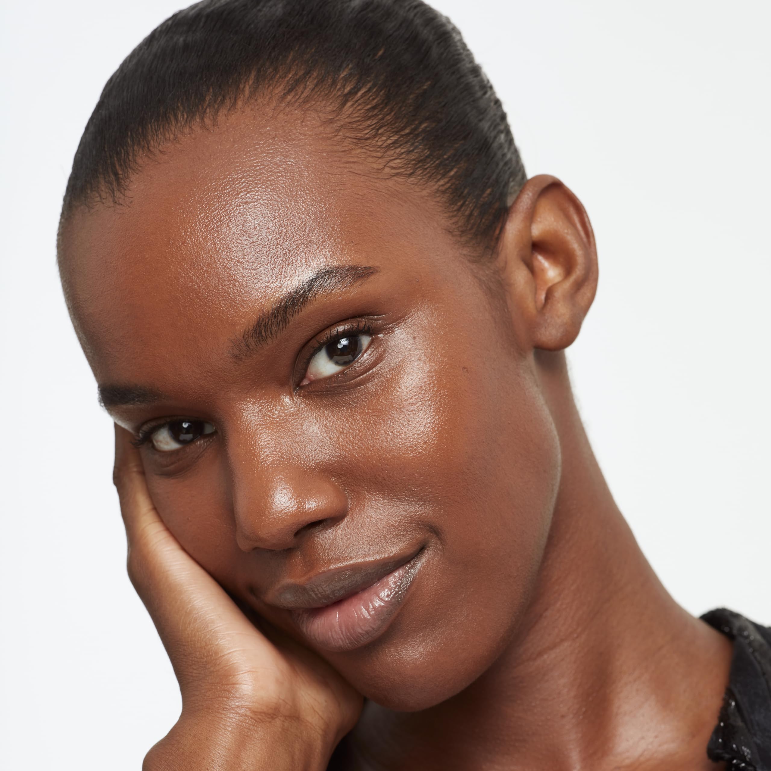 Application shot of Saie Glowy Super Skin Tint swirled on skin for natural glow.